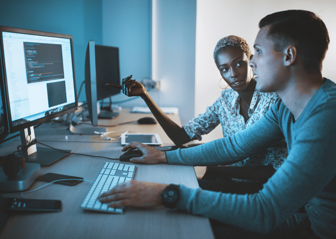 Two web developers discuss a block of coding.