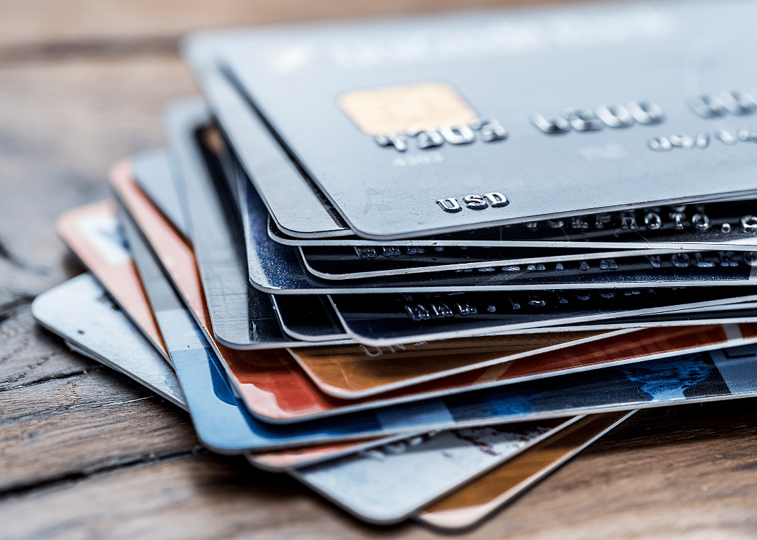 A stack of multiple credit cards on a wooden surface.