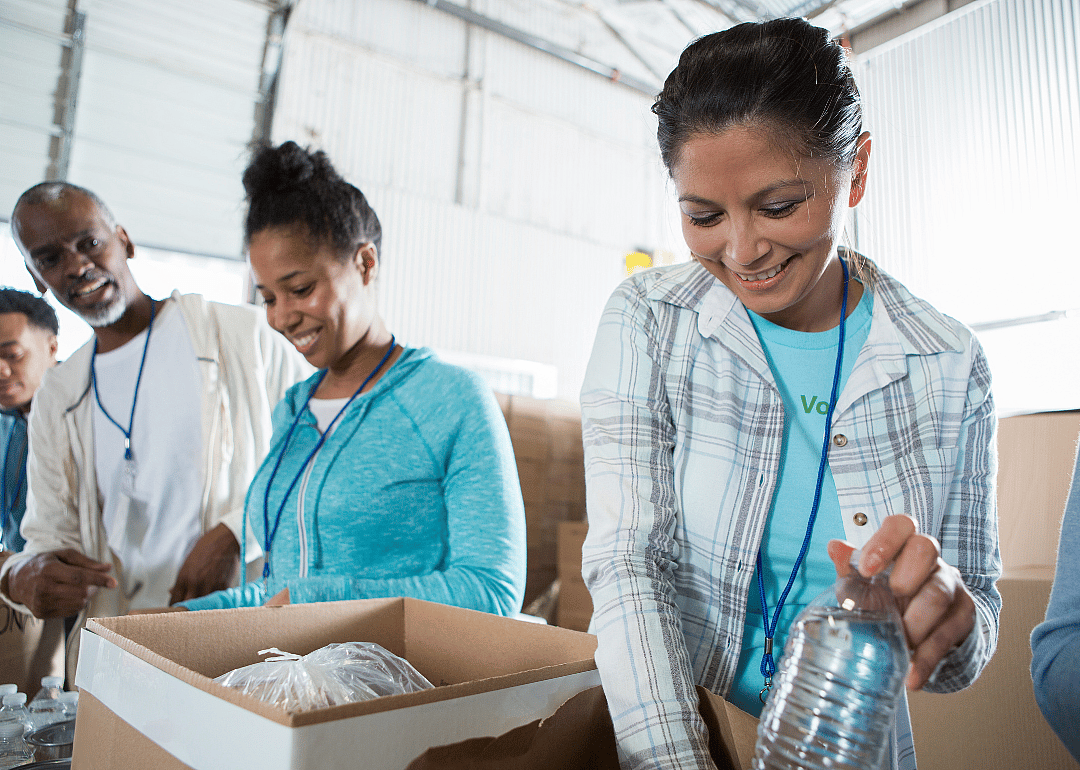 Three people help pack food at a food pantry.