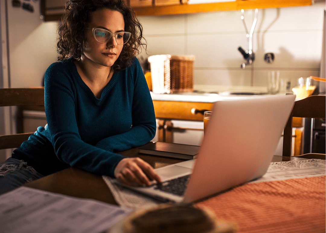 A young woman studies information on a laptop.