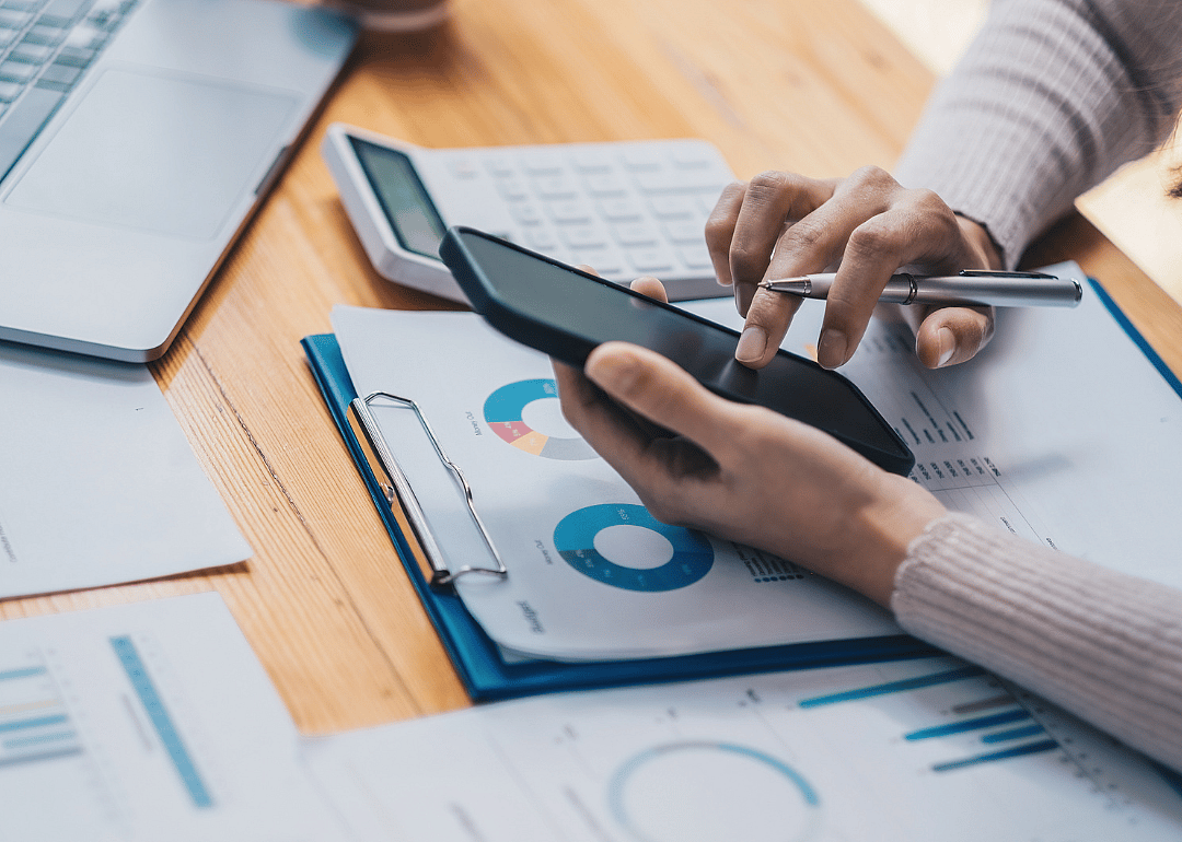 Close up of person at a desk using a calculator.