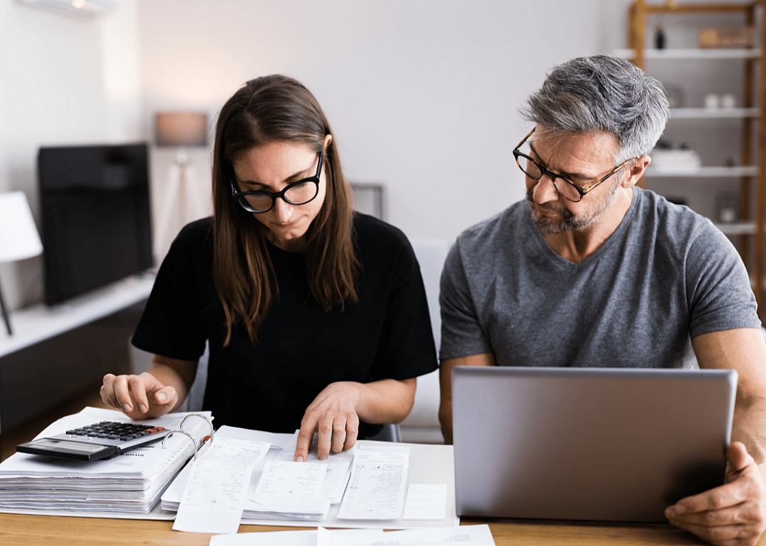A couple sits at a table reviewing financial papers.