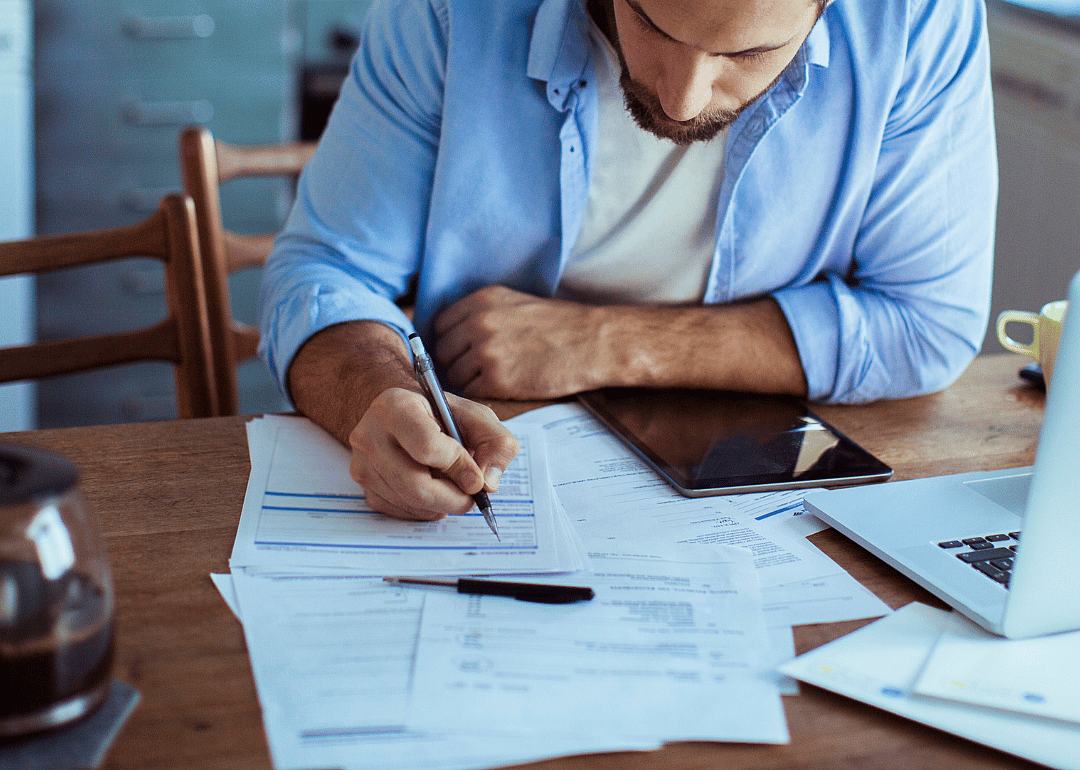 A person reviewing his finances with a laptop and papers.