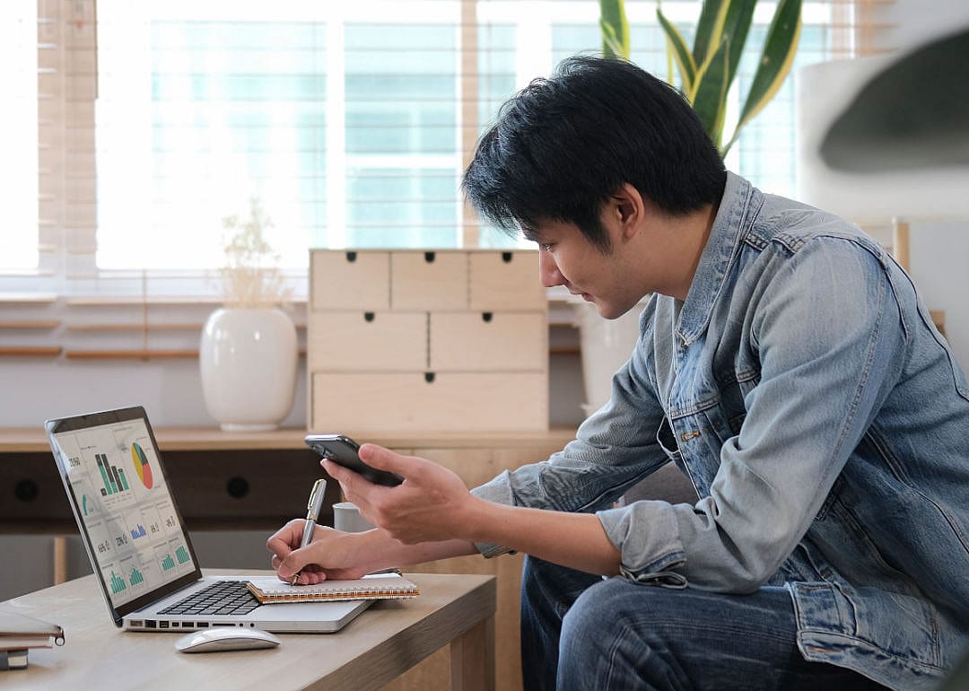 A millennial man searching information online, working with computer laptop.