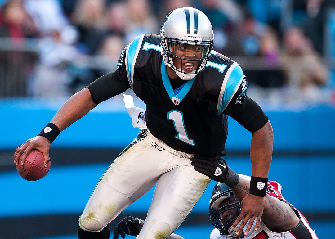 Quarterback Cam Newton #1 of the Carolina Panthers scrambles away from the rush by John Abraham #55 of the Atlanta Falcons.