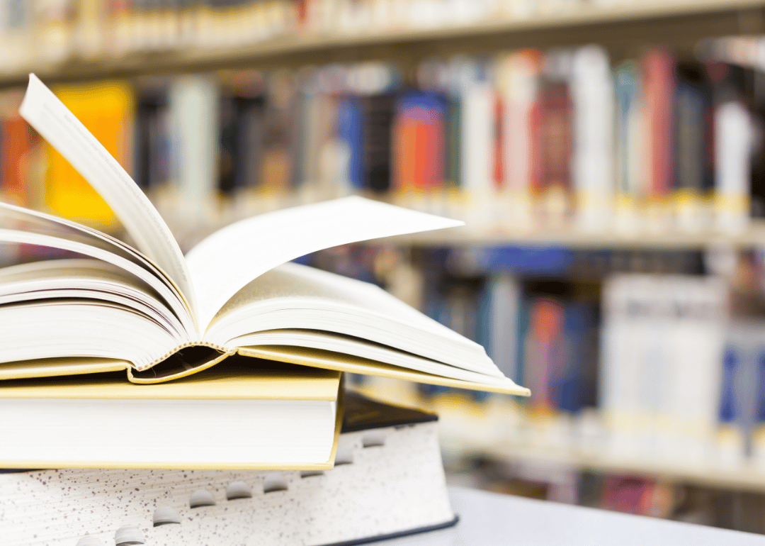 A stack of textbooks with an open one on top.