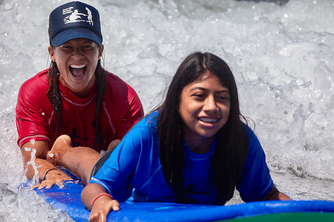 Surfing therapist Kris Primacio helps a young girl on a body board