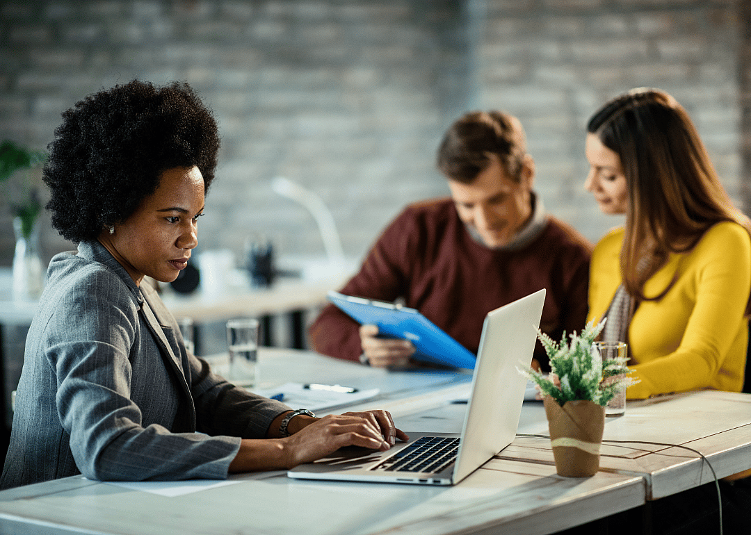 A financial advisor consults her laptop during a meeting with clients.