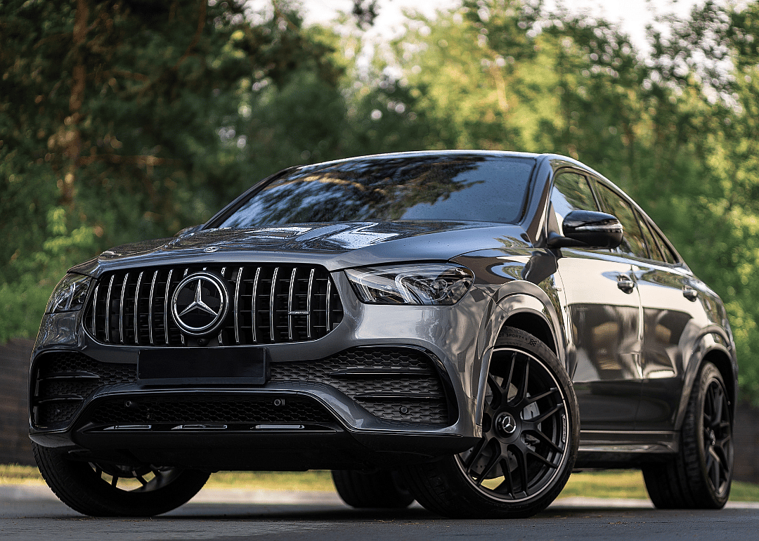 A silver Mercedes-Benz GLE Coupe AMG 53 4Matic+ 2023 parked on the forest on a warm summer day