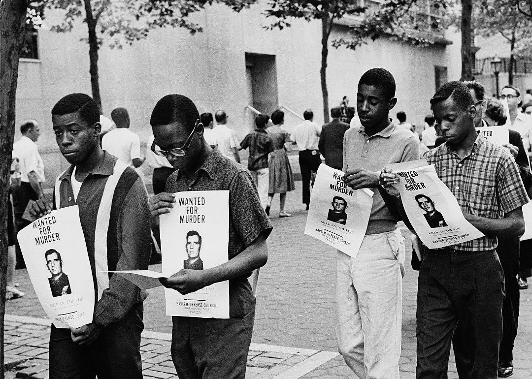 Demonstrators carrying posters with a picture of police Lieutenant Thomas Gilligan and the caption 'Wanted For Murder' outside the UN Headquarters in New York City, during the Harlem Riots, 23rd July 1964. 