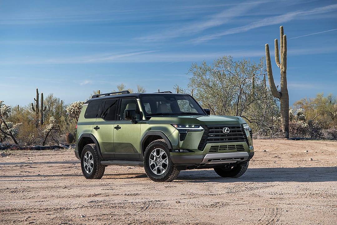 Green Lexus GX parked in desert with Saguaro cactus in background.