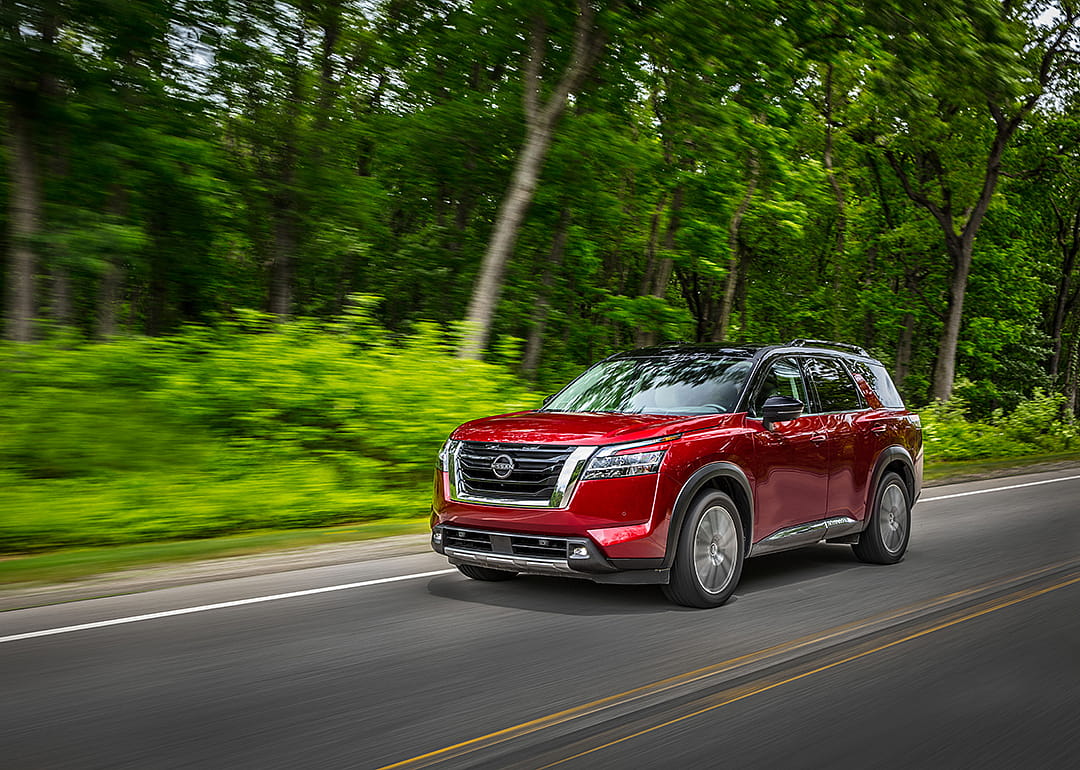 A red 2023 Nissan Pathfinder driven on the road.