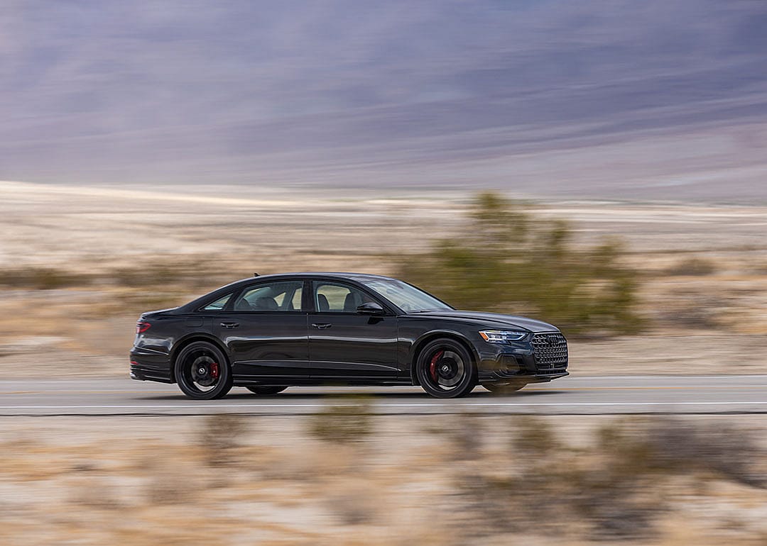 A black Audi S8 being driven on a road.