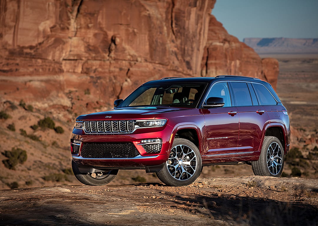 A red 2025 Jeep Grand Cherokee Summit parked on a desert road.