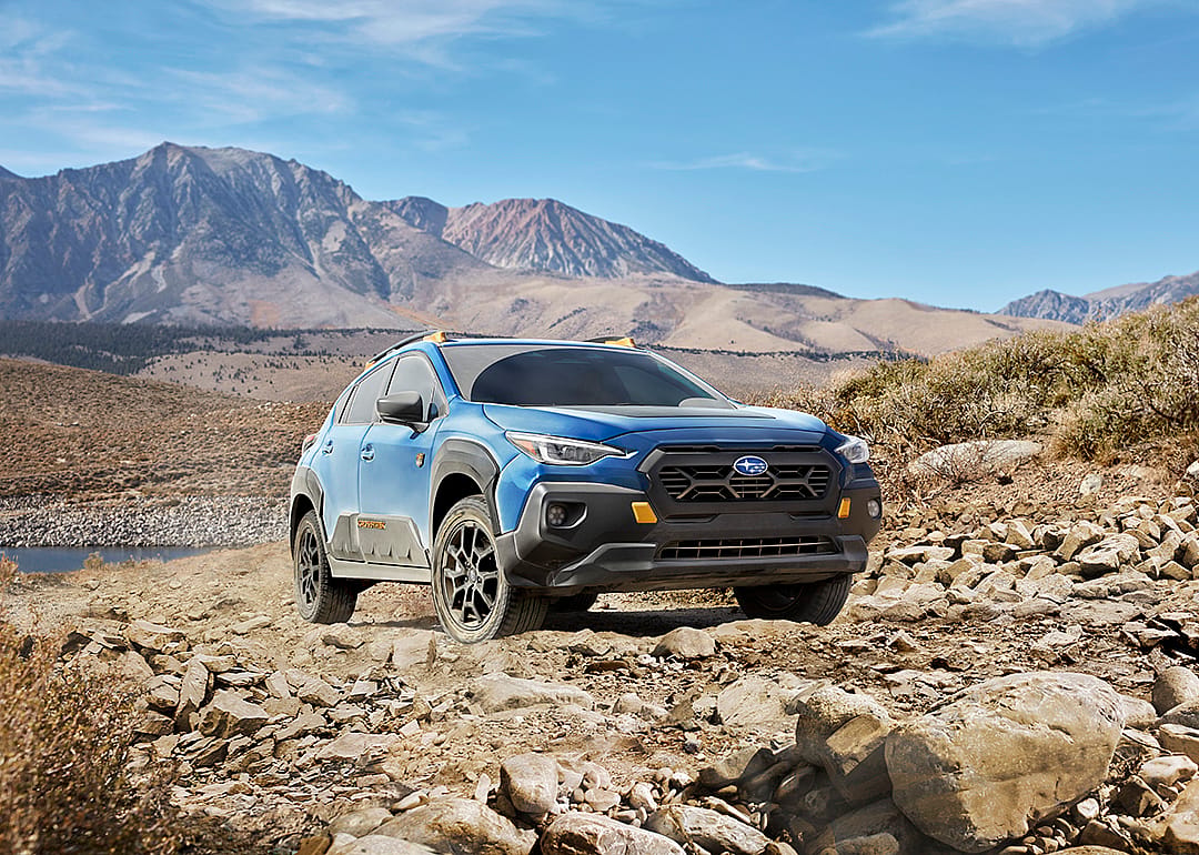 A blue 2025 Subaru Crosstrek parked on a lakeside.