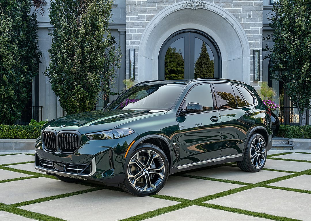 Dark green BMW X5 parked in front of home.
