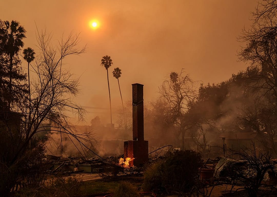A brick chimney remains while the surrounding area of a home still burns during the Eaton fire.