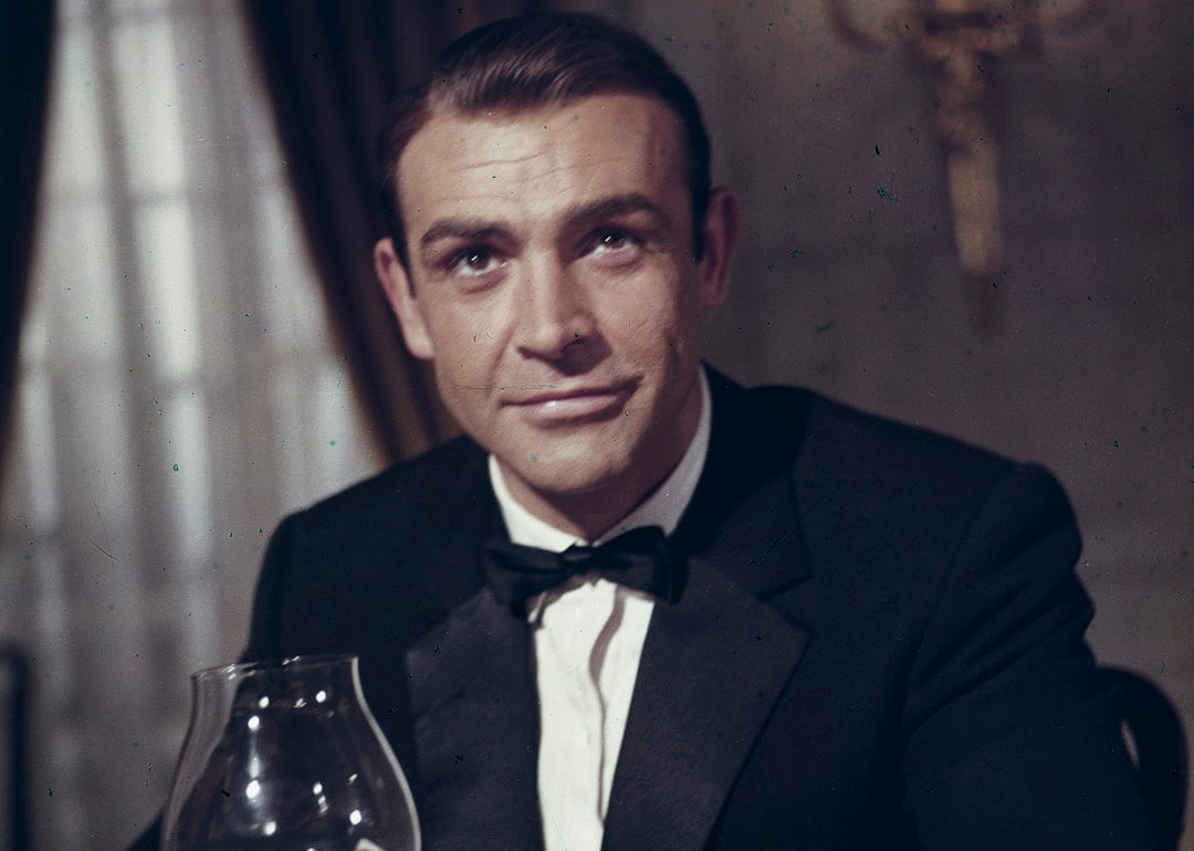 Sean Connery wearing a tuxedo and holding a glass of brandy as James Bond 007 in 'Goldfinger.'
