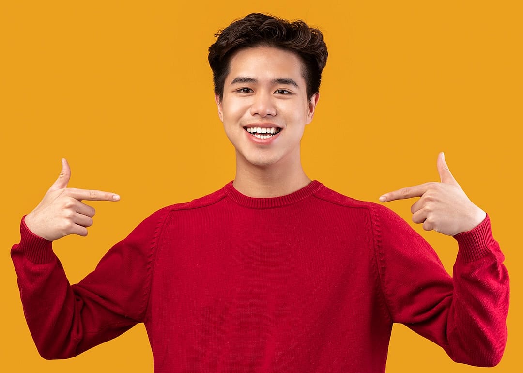 Smiling, self-assured teen pointing at himself confidently.