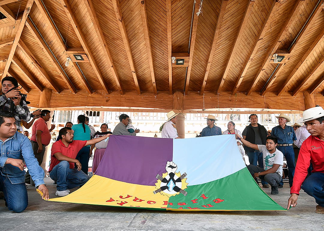 twelve members of the recently elected Purepecha indigenous council, display a Purepecha flag.