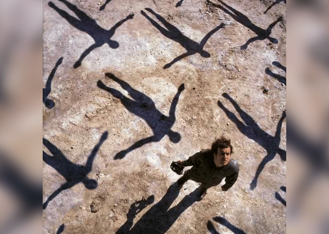 A man surrounded by shadows looking up at the sky.