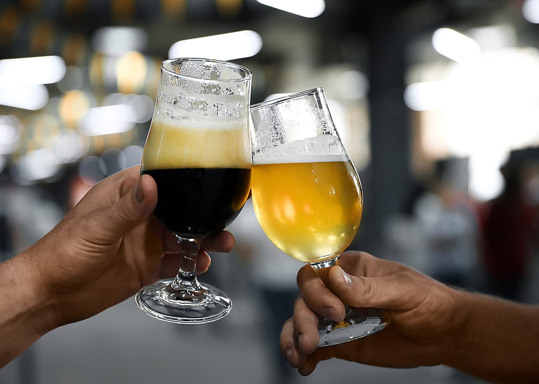 Hands with glass of dark and light beers.