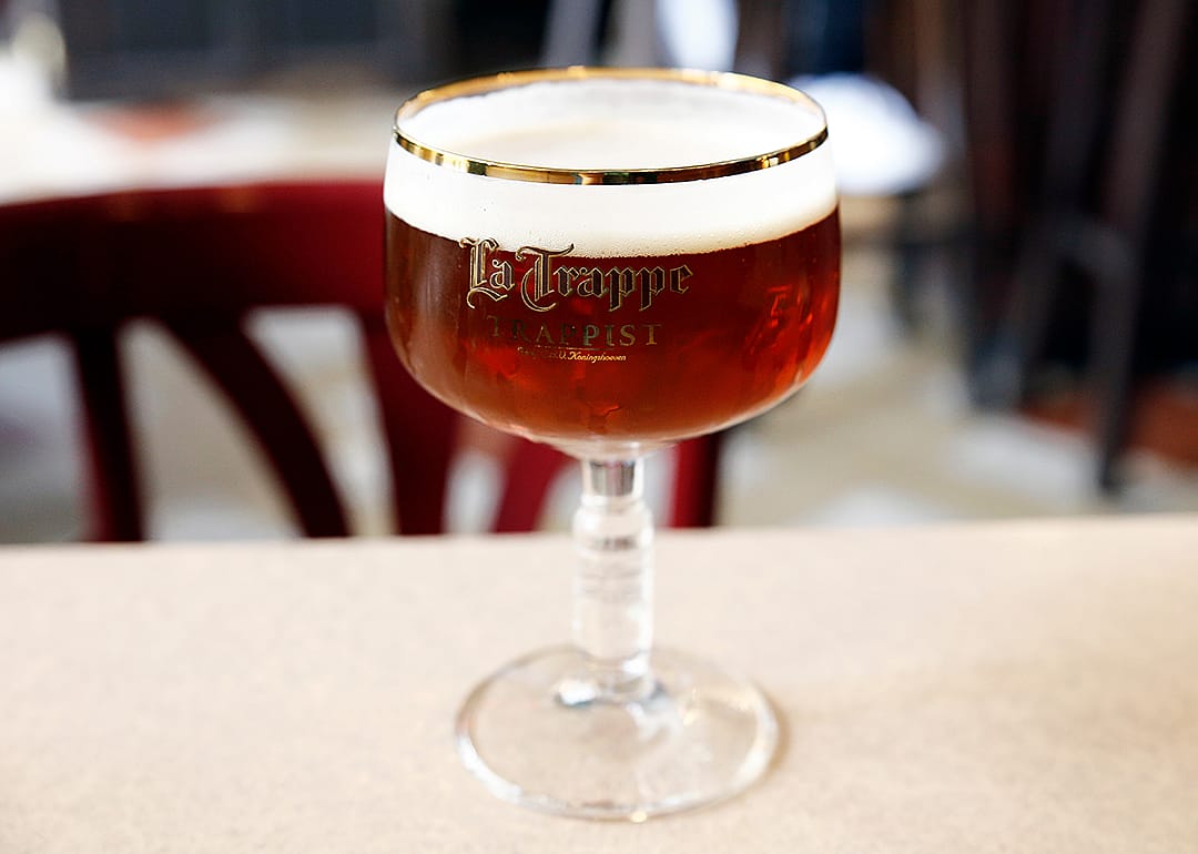 A glass of La Trappe Quadrupel beer on a table.