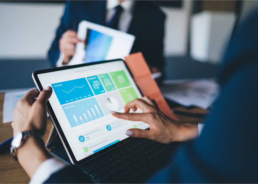 Person reviewing reports on tablet in business meeting.