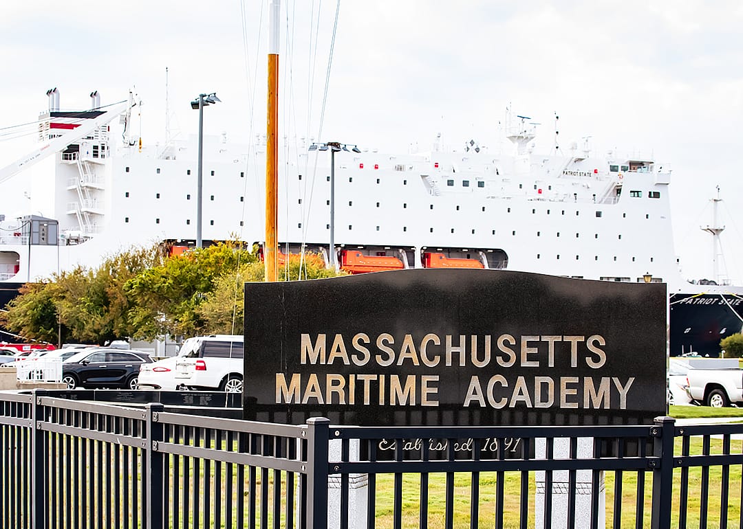 Massachusetts Maritime Academy sign with ship in background.