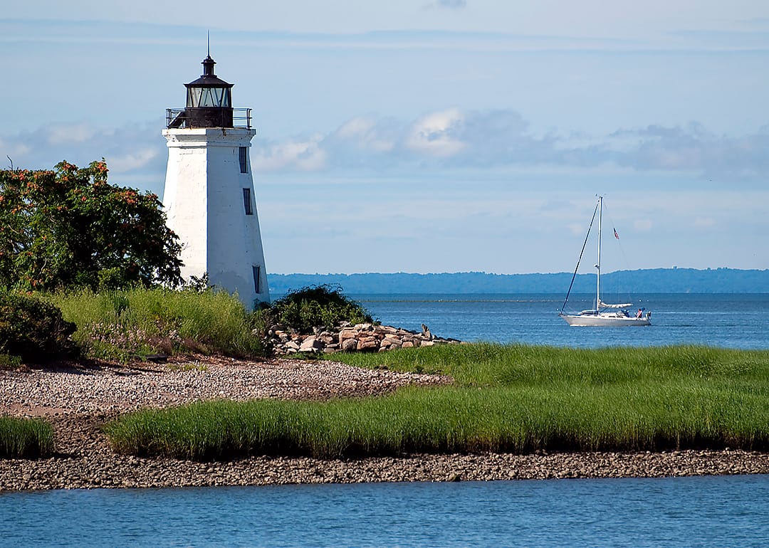 Sailboat passing by tower of Black Rock Harbor lighthouse.