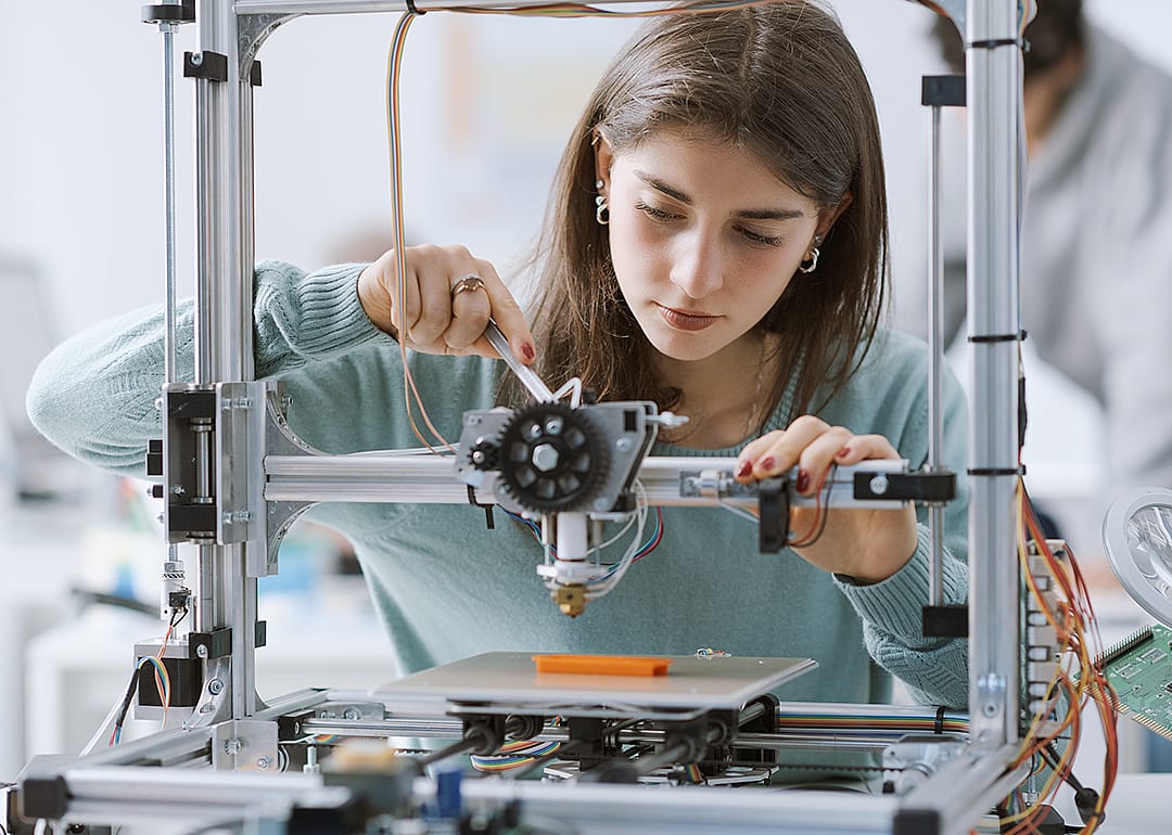 Student working with a 3D printer in the lab.