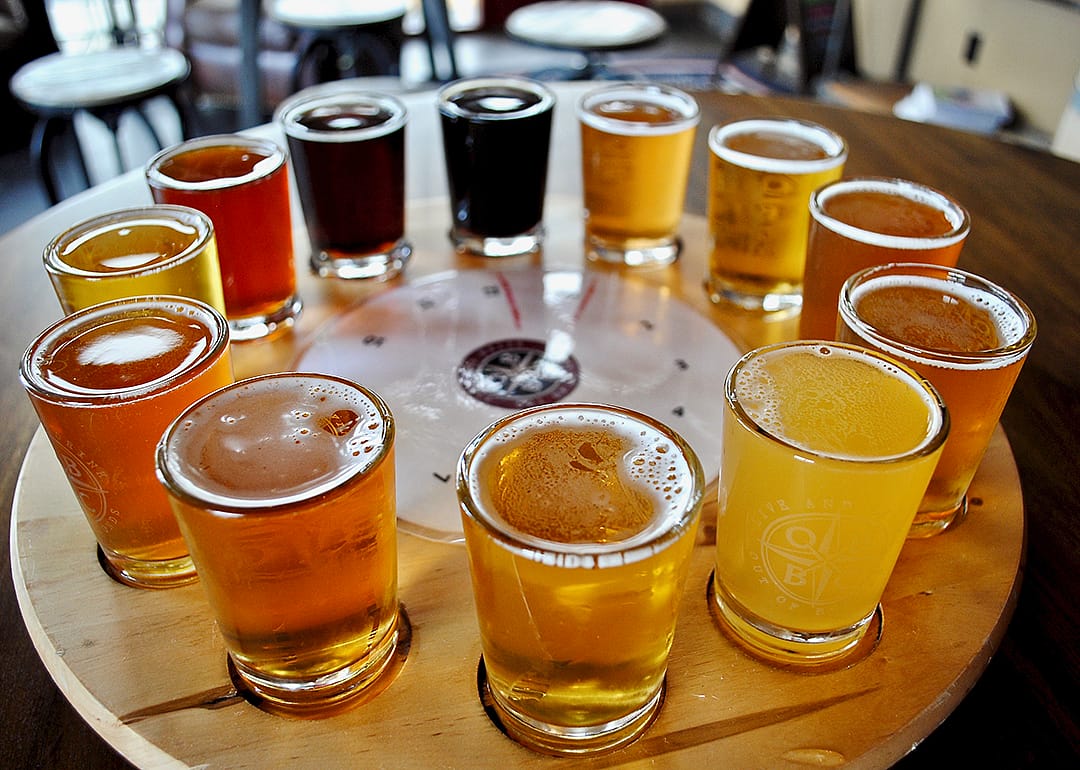A flight of beer samples on a wooden table.
