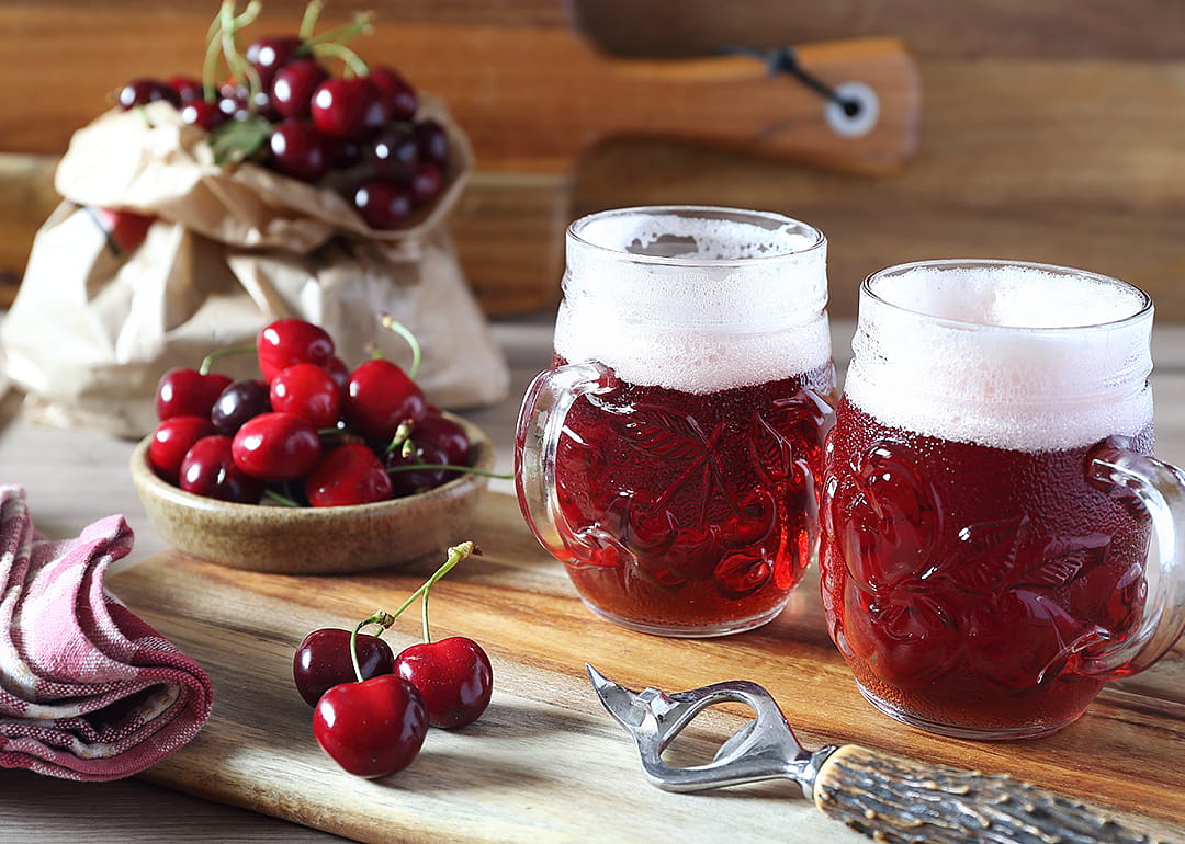 Fruit craft beer and cherry on wooden chopping board.