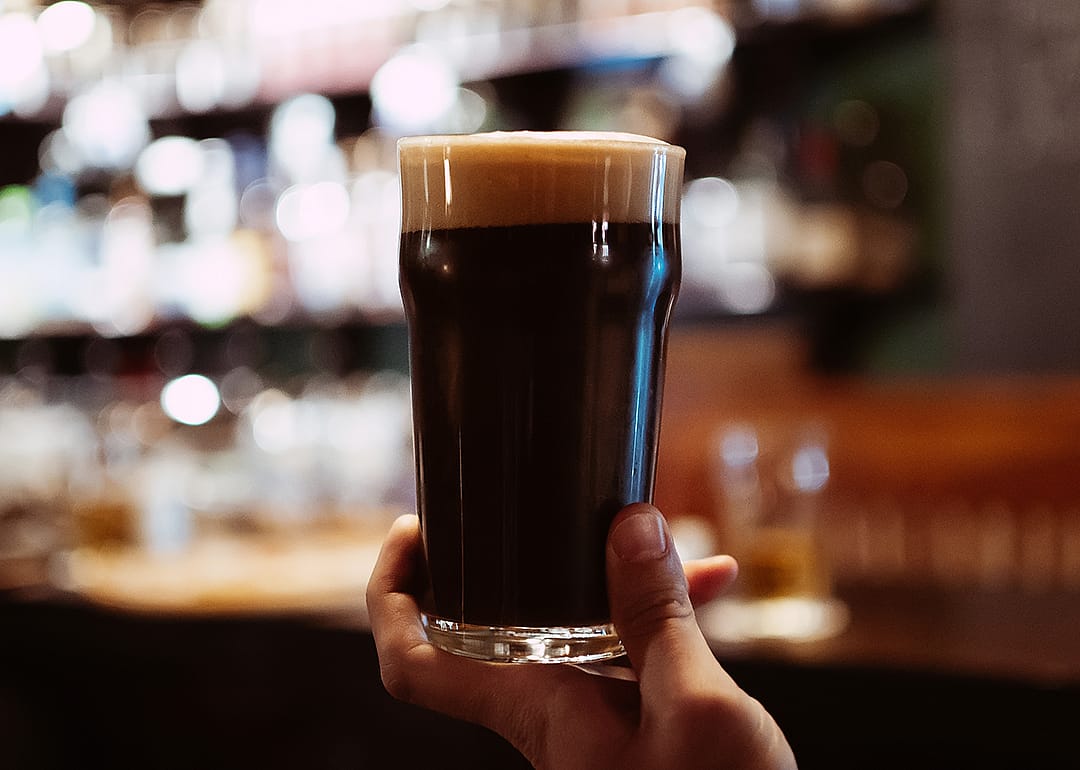 Glass of dark stout beer with foam.