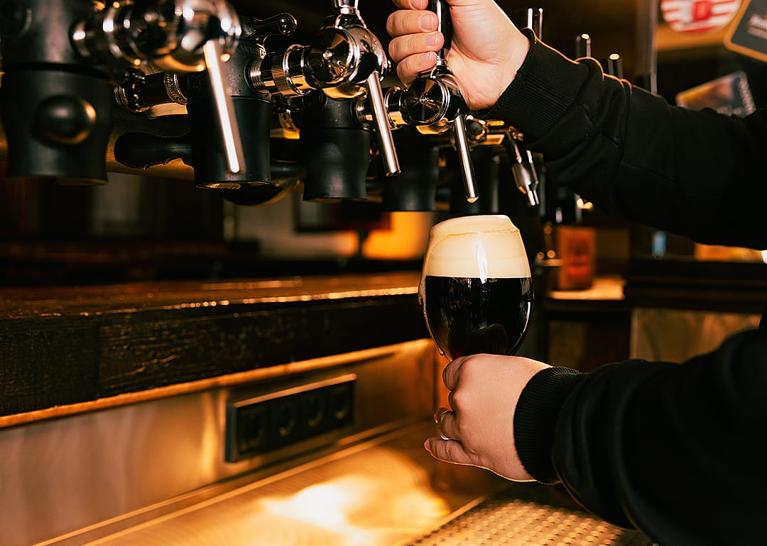 Bartender filling pint with stout.