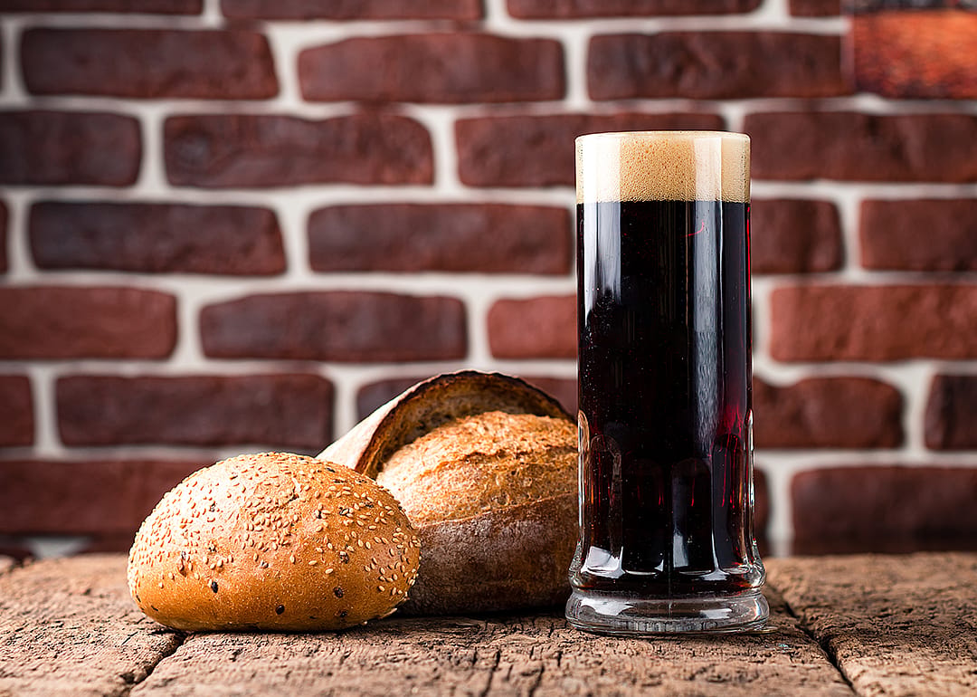 Rye beer in a glass with bread on table.