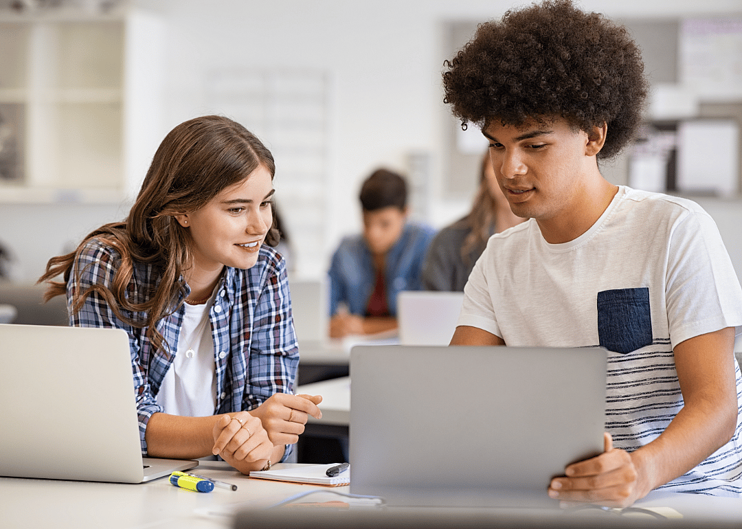 Two students share a laptop.