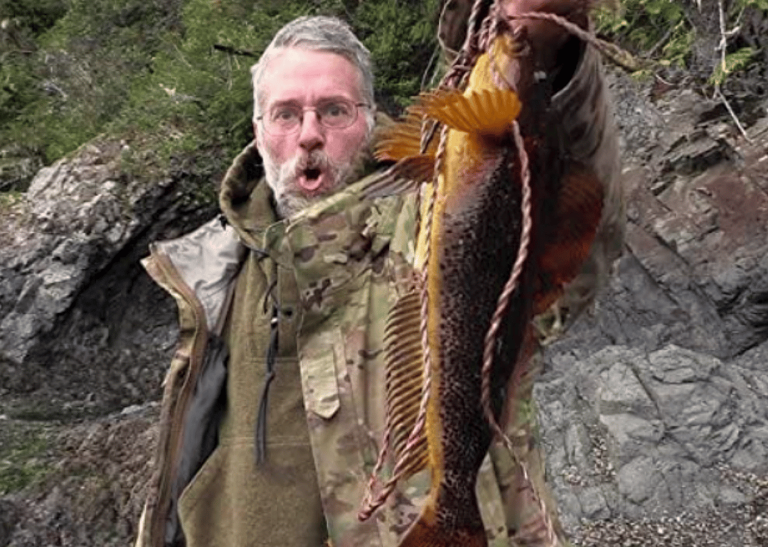 A contestant holds up a fish in the wild