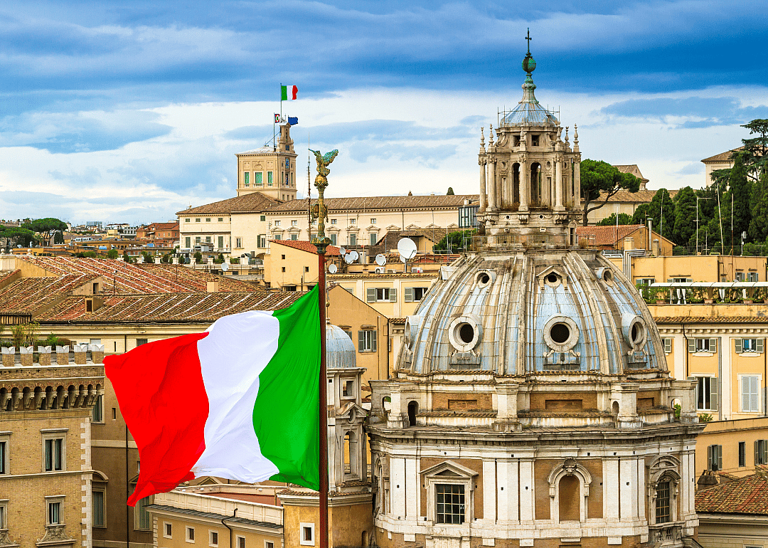 Red, white and green flag flying in front of a dome.