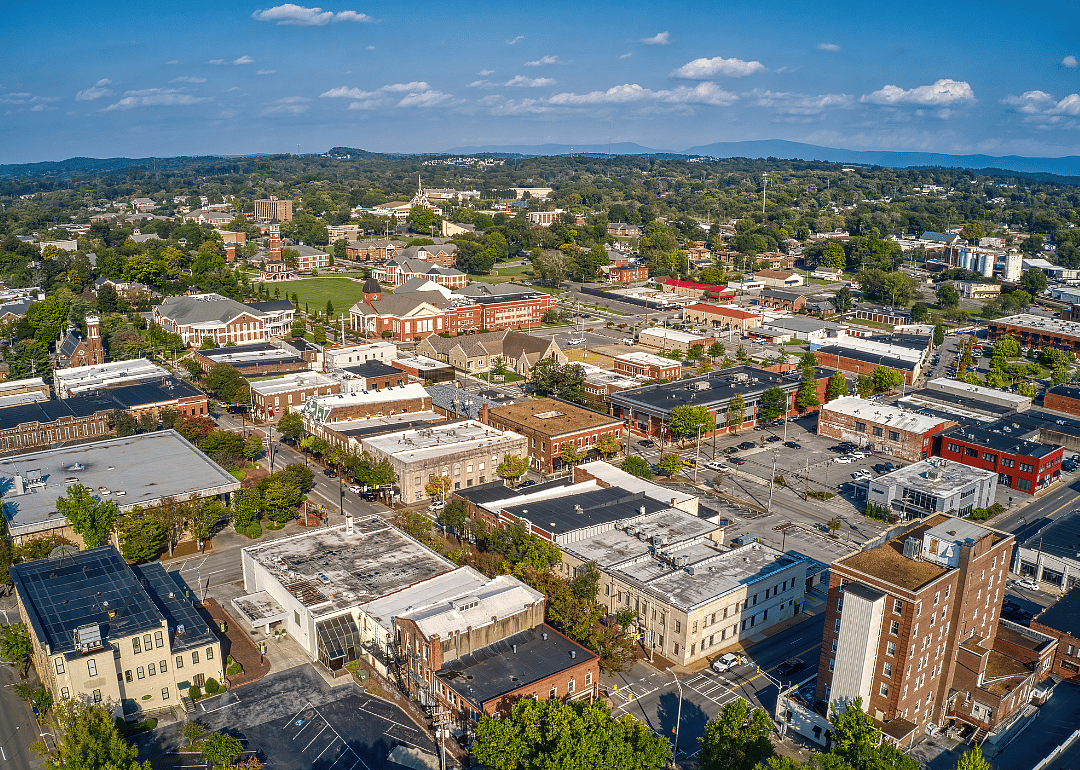 Aerial view of a city with green trees and mountains in the far background.