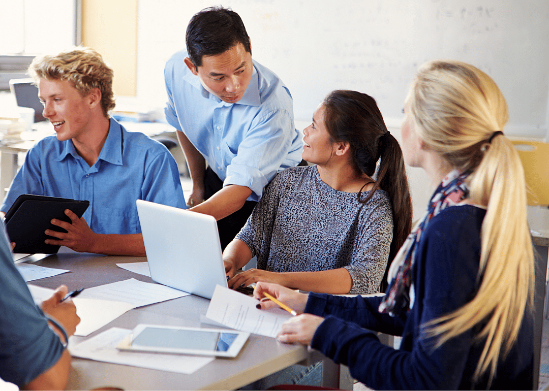 Students with laptops and tablets receive instruction from a professor.