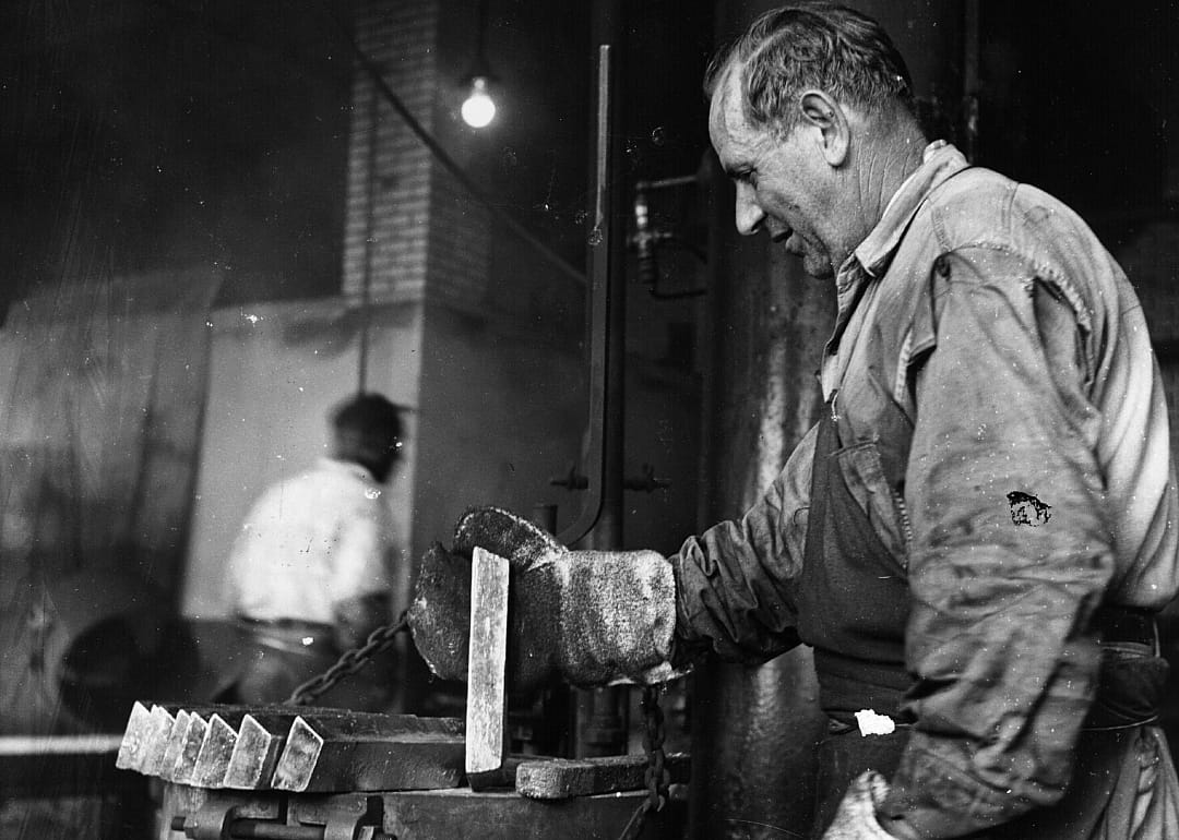 A worker forges some gold bars.
