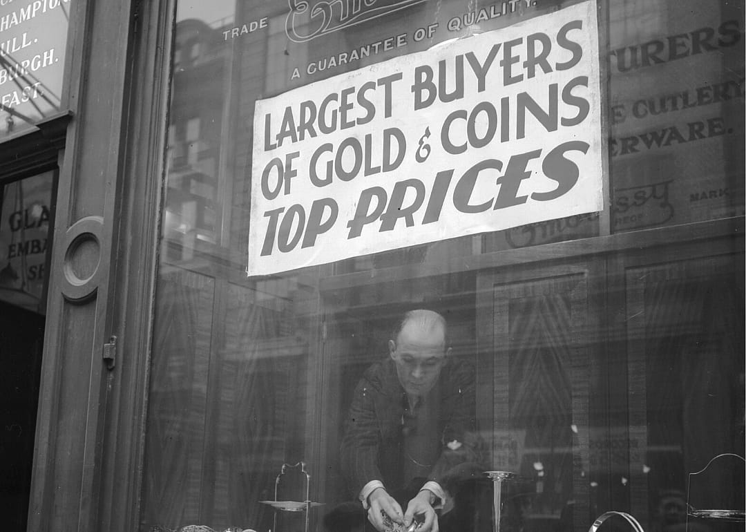 A shop worker removes coins from a window display.