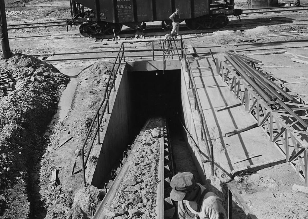 A mine worker monitors a conveyor belt of material.
