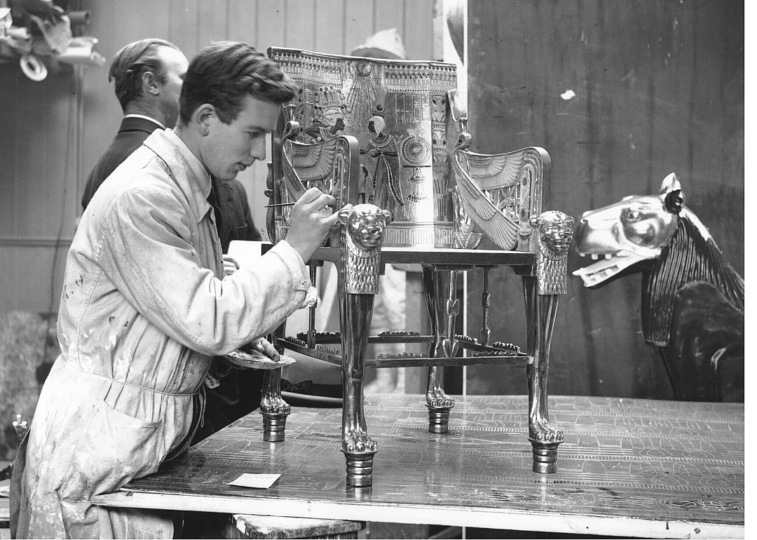 A worker cleans an Egyptian artifact made of gold.
