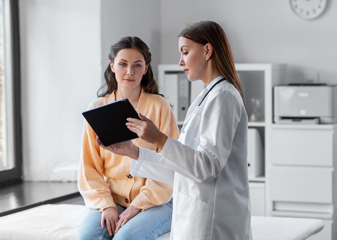 Female doctor with tablet speaking with a patient.