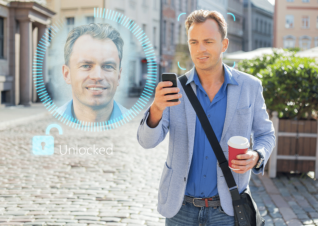 A man holding a phone in his hand with a close up of his face next to him. 