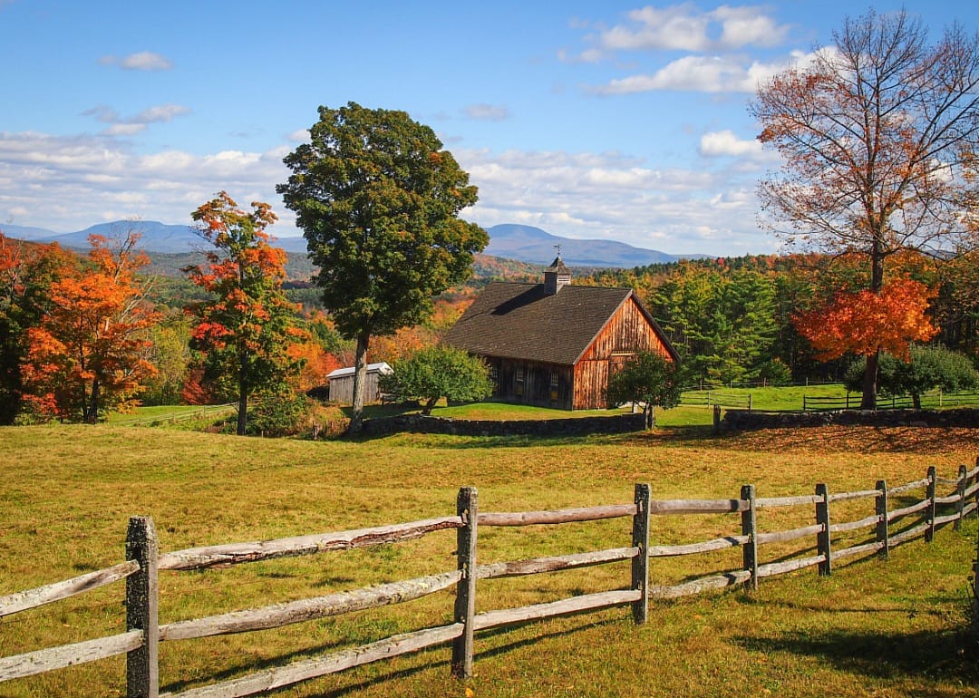 A historic building and wooden fence surrounded by Fall foliage.