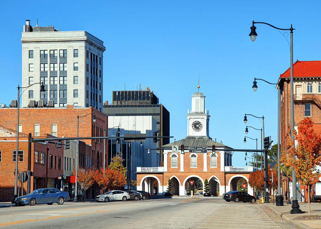 Red brick buildings along the street with a tall white building in the background.