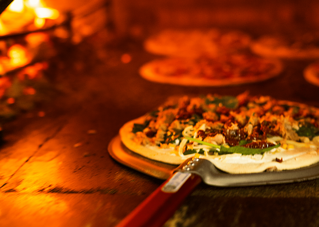 Sausage pizza being pulled out of the oven.